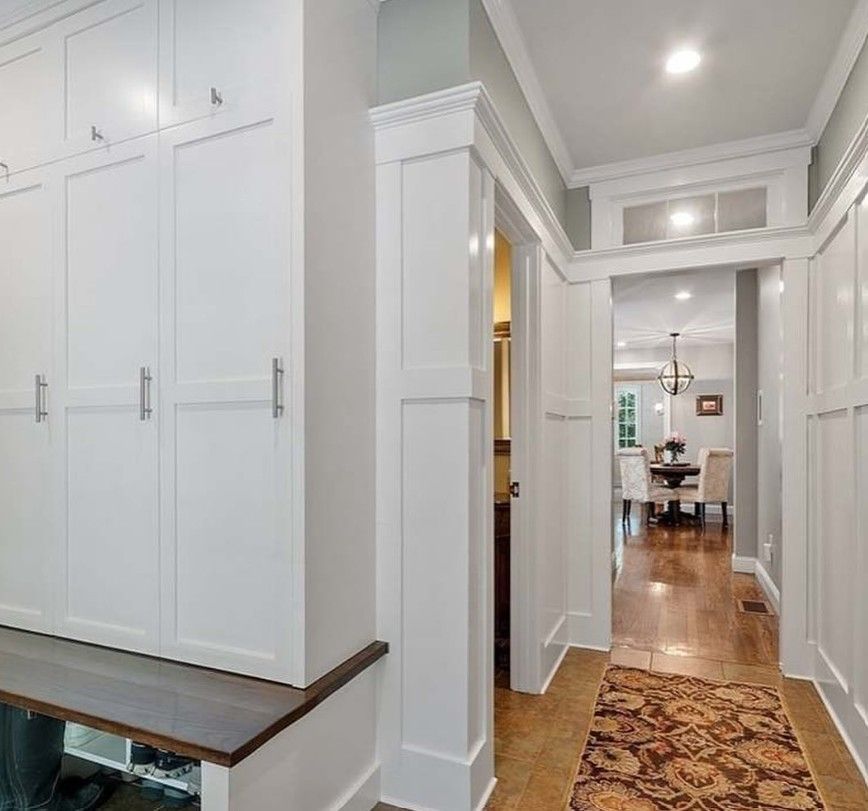 Hallway with white cabinets, built-in bench, and doorway leading to a dining room with a chandelier.