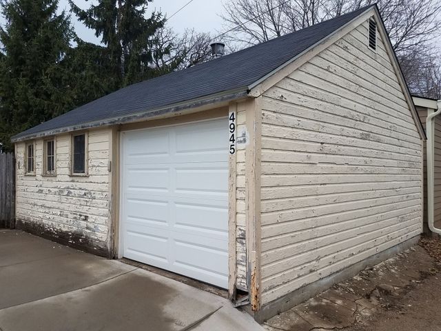 Cream-colored garage with a white door, three small windows, and a dark roof. Address numbers 4345 are on the side.