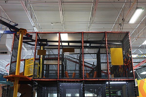 A large indoor playground with a ropes course and a slide.