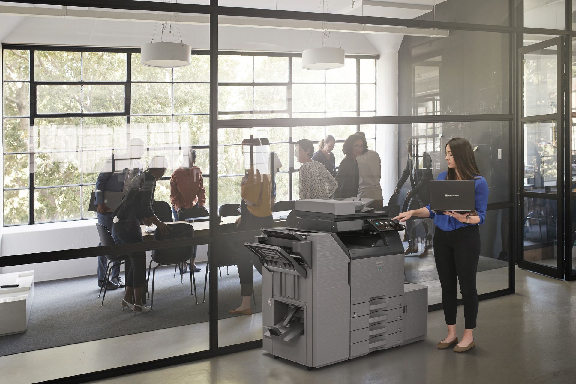 A woman is standing in front of a printer in an office.