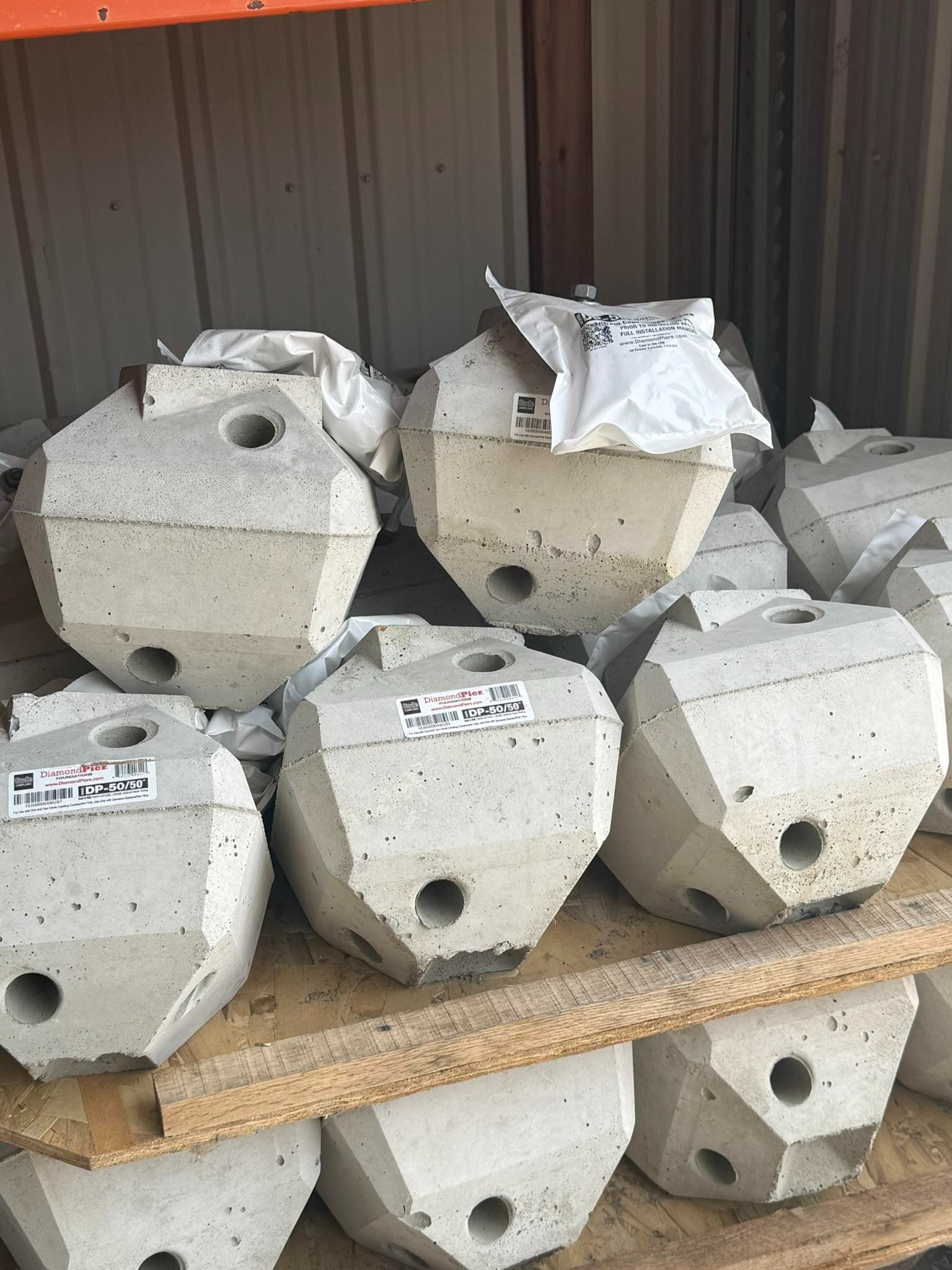Stacked gray concrete blocks with circular holes and white bags in a metal storage area
