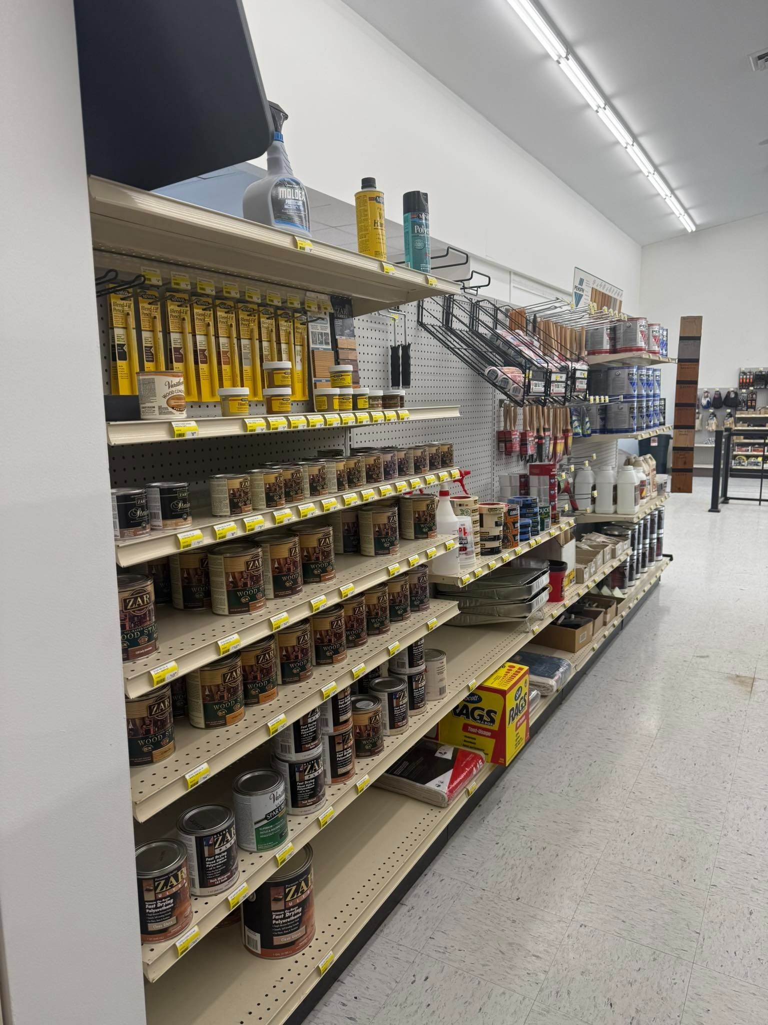 Aisle of home goods shelves stocked with bottles, cans, and cleaning supplies in a store.