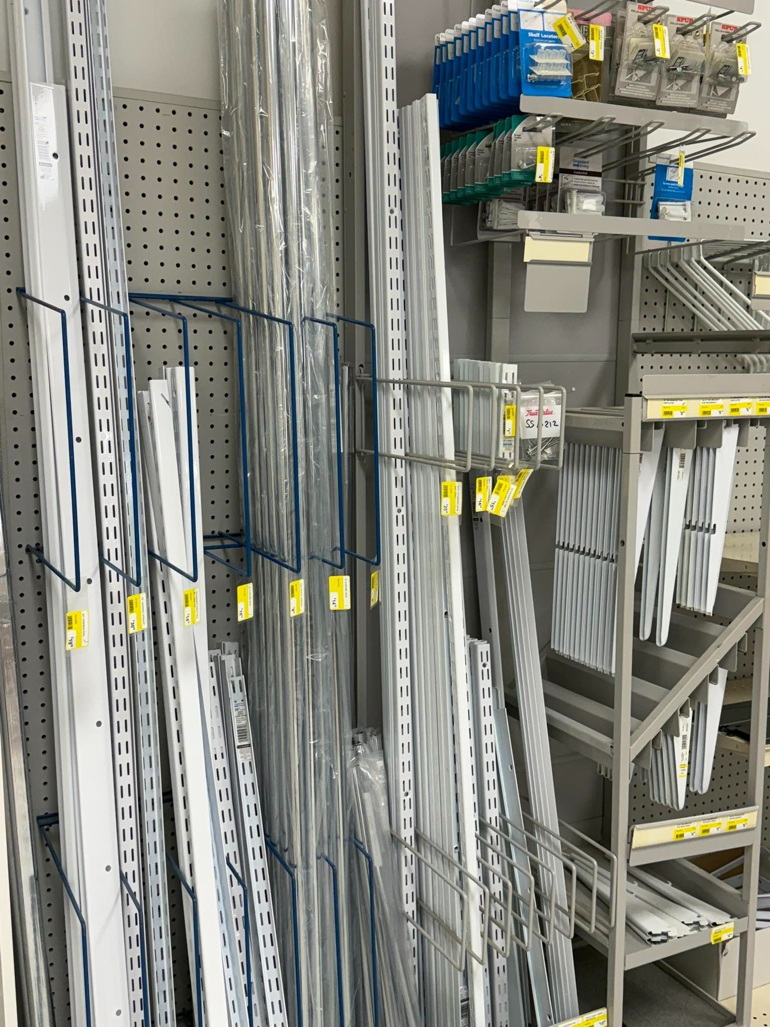 Industrial shelving with rows of long white and gray metal strips and yellow-labeled bins in a warehouse.