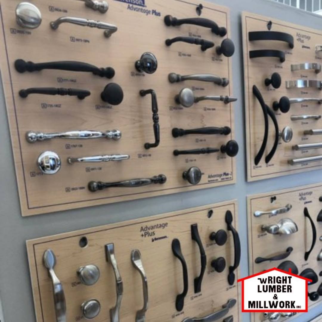 Display of assorted cabinet and door handles mounted on tan boards in a hardware store.