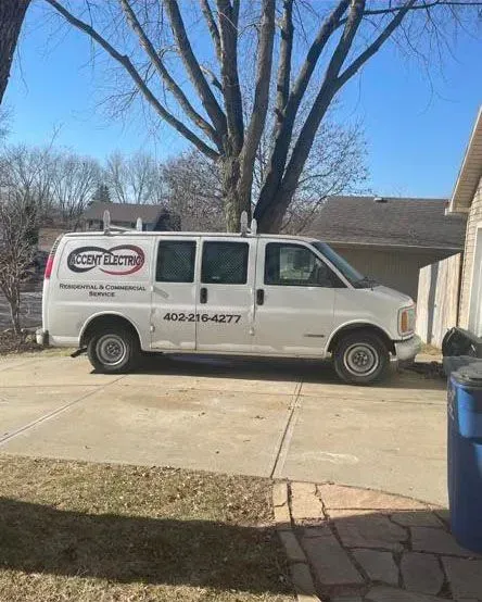 A white work van parked in a residential driveway, labeled with a logo and phone number for 