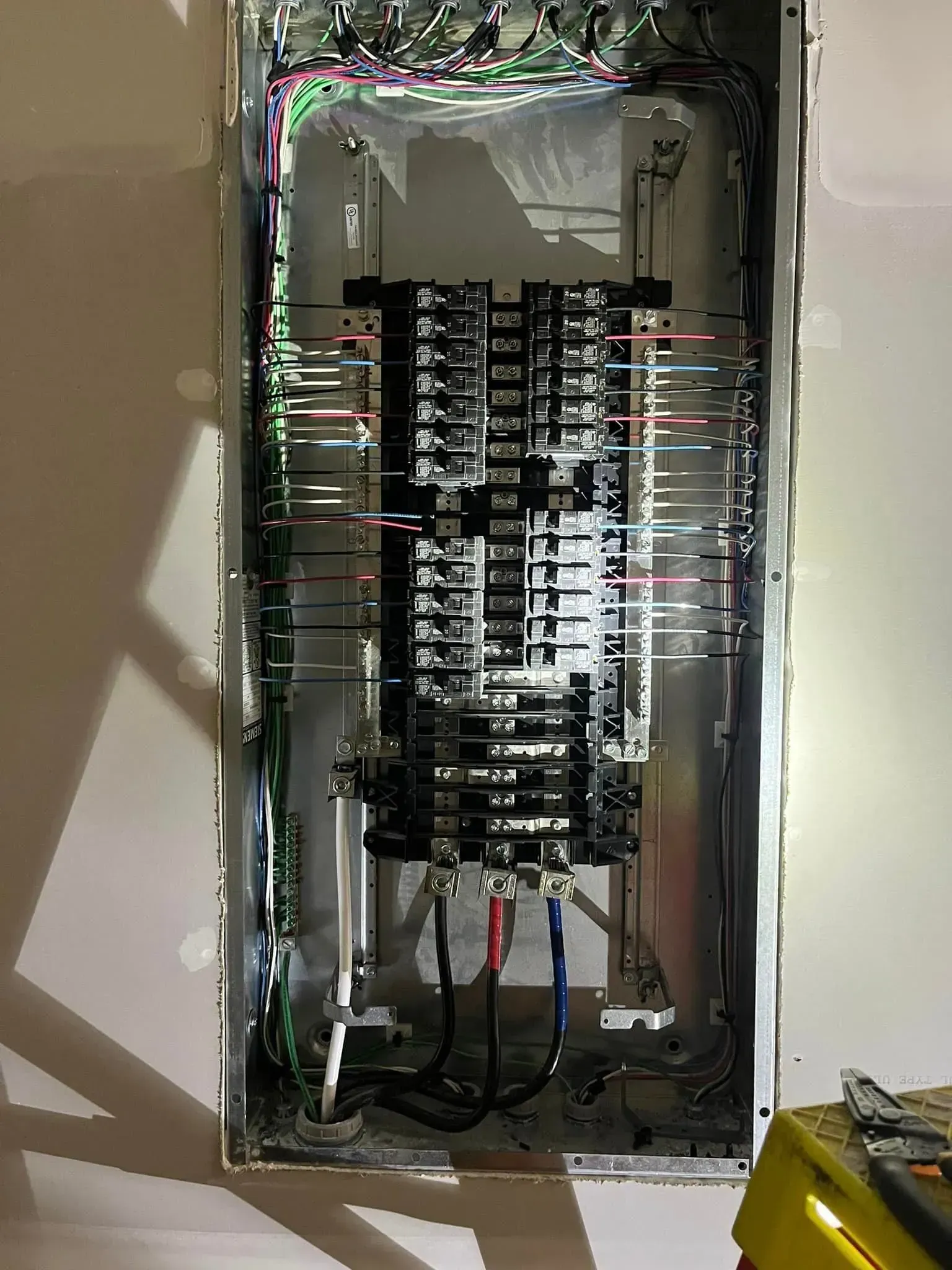 An open electrical breaker panel with multiple wires connected to the central terminal bus and main power cables below.