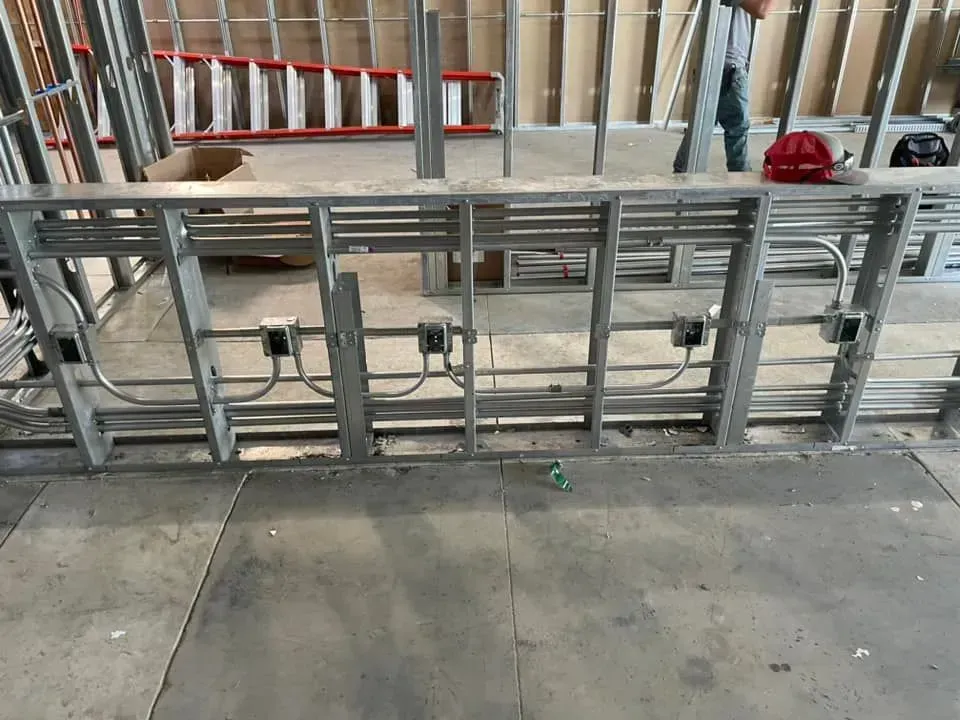 Electrical metal tubing and junction boxes installed on metal wall studs in a construction setting.