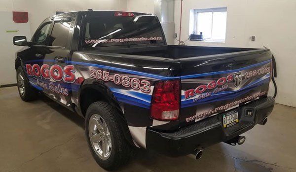 A black and blue truck is parked in a garage.