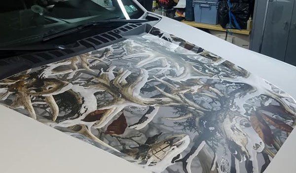 The hood of a white truck with a camouflage design on it.