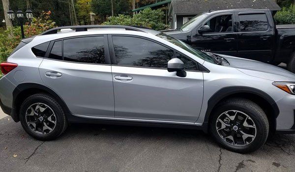 A silver suv is parked next to a black truck.