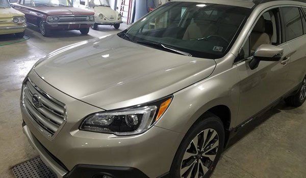 A silver subaru outback is parked in a garage.