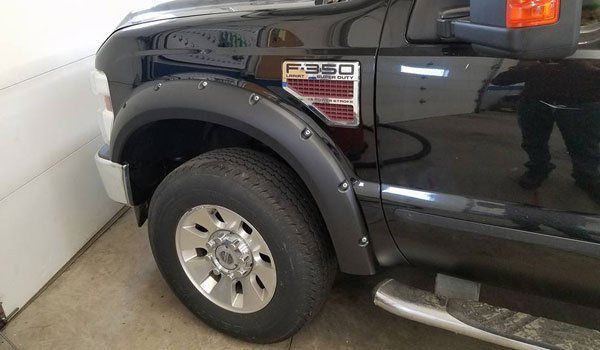 A black ford f250 truck is parked in a garage.