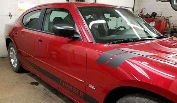 A red dodge charger is parked in a garage