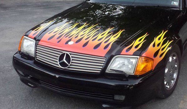 A black mercedes with flames painted on the hood