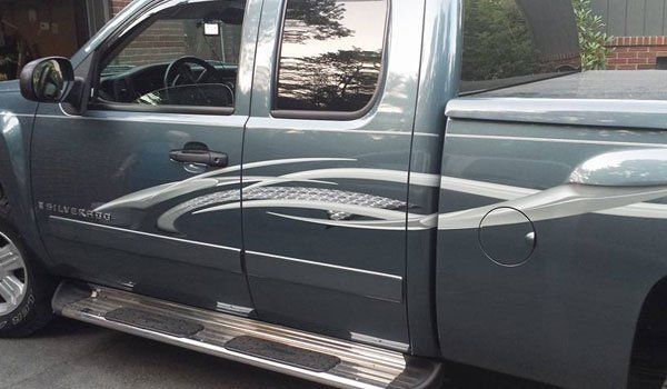 A blue truck is parked in front of a house.