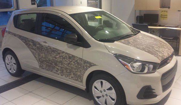 A small white car is parked in a showroom.