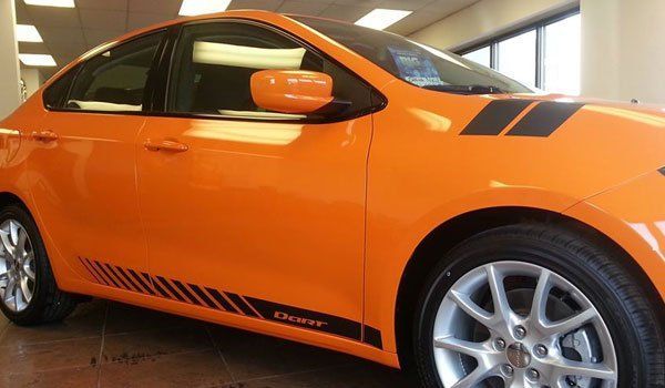 An orange dodge dart is parked in a showroom