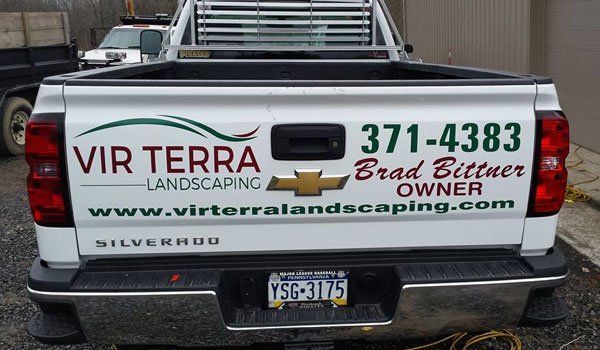 A white truck with a chevrolet logo on the back is parked in a parking lot.