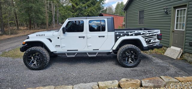 A white jeep gladiator is parked in front of a house.
