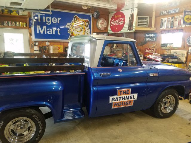 A blue truck with the rathmel house written on the side is parked in a garage