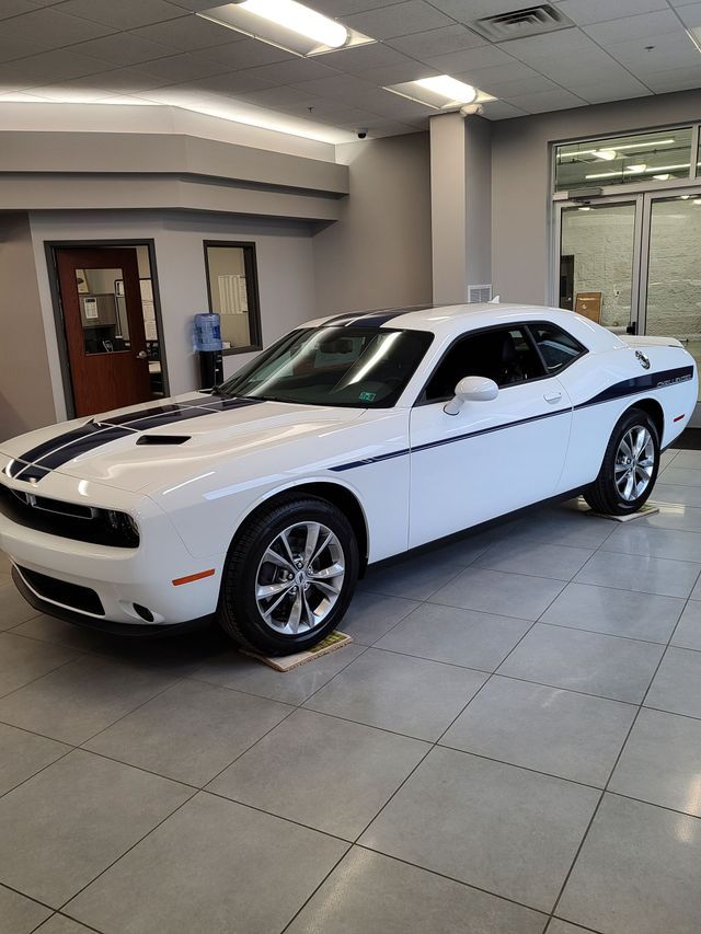 A white dodge challenger is parked in a showroom.