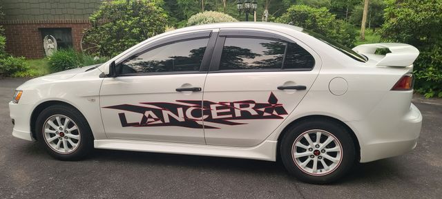 A white lancer is parked in a parking lot.