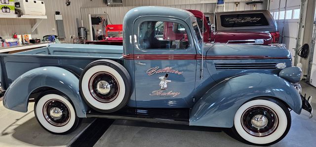 A blue truck with white tires is parked in a garage.