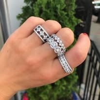 Hand displaying three diamond rings with various designs.