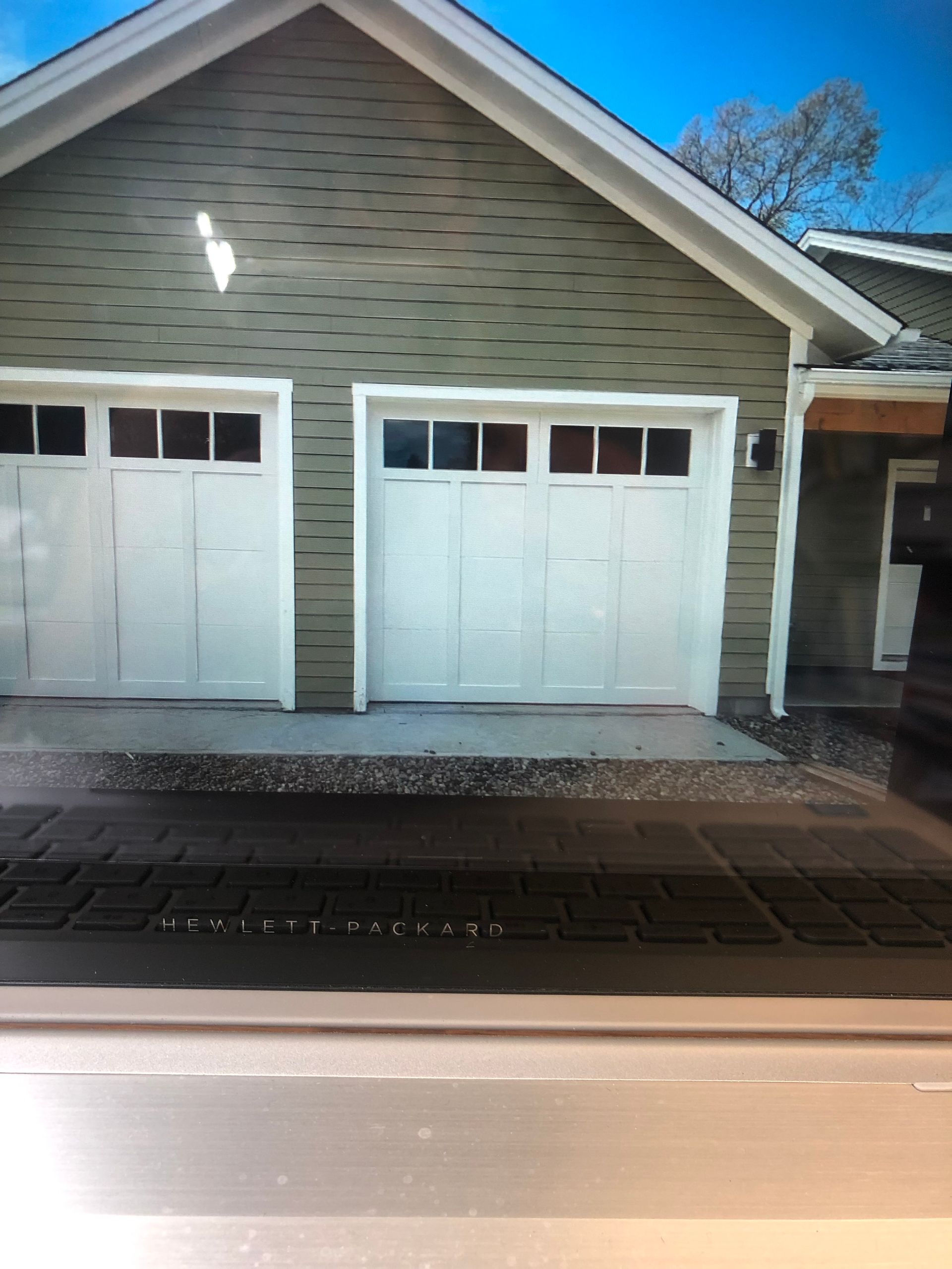 Two-car garage with white doors, green siding, and concrete driveway.