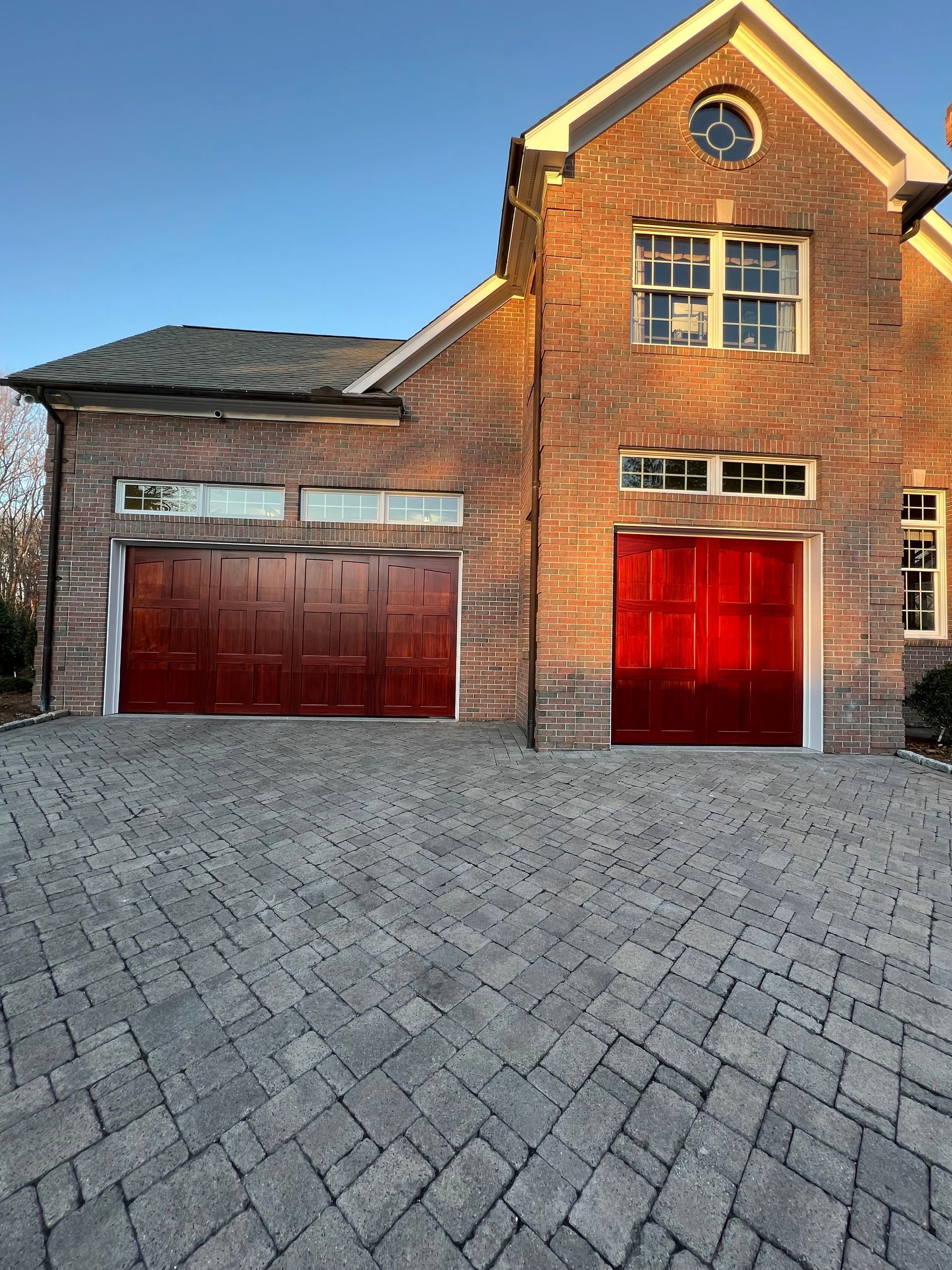 Brick house with red garage doors and a brick driveway.