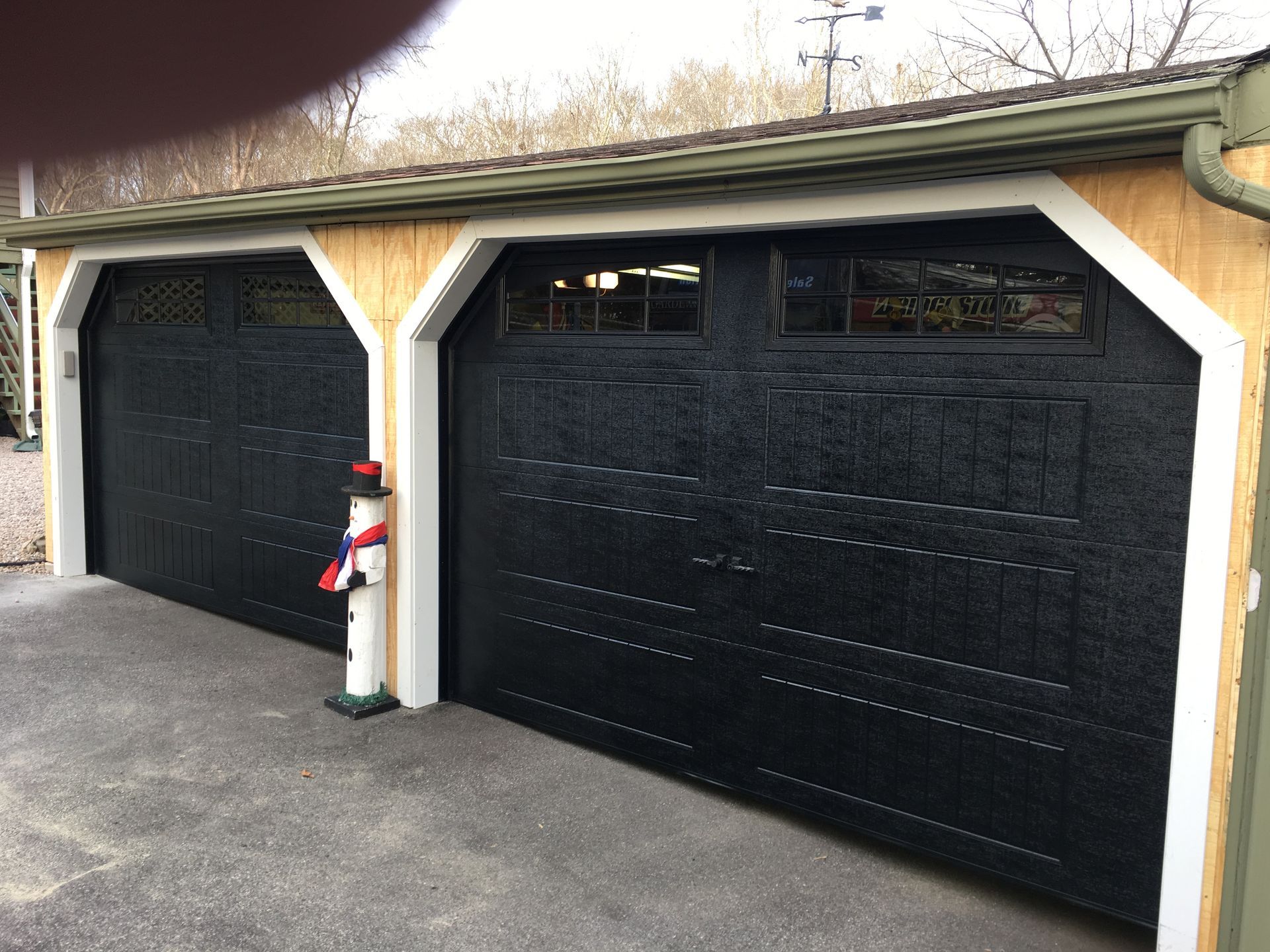 Black garage doors with small windows, on a tan garage with white trim.