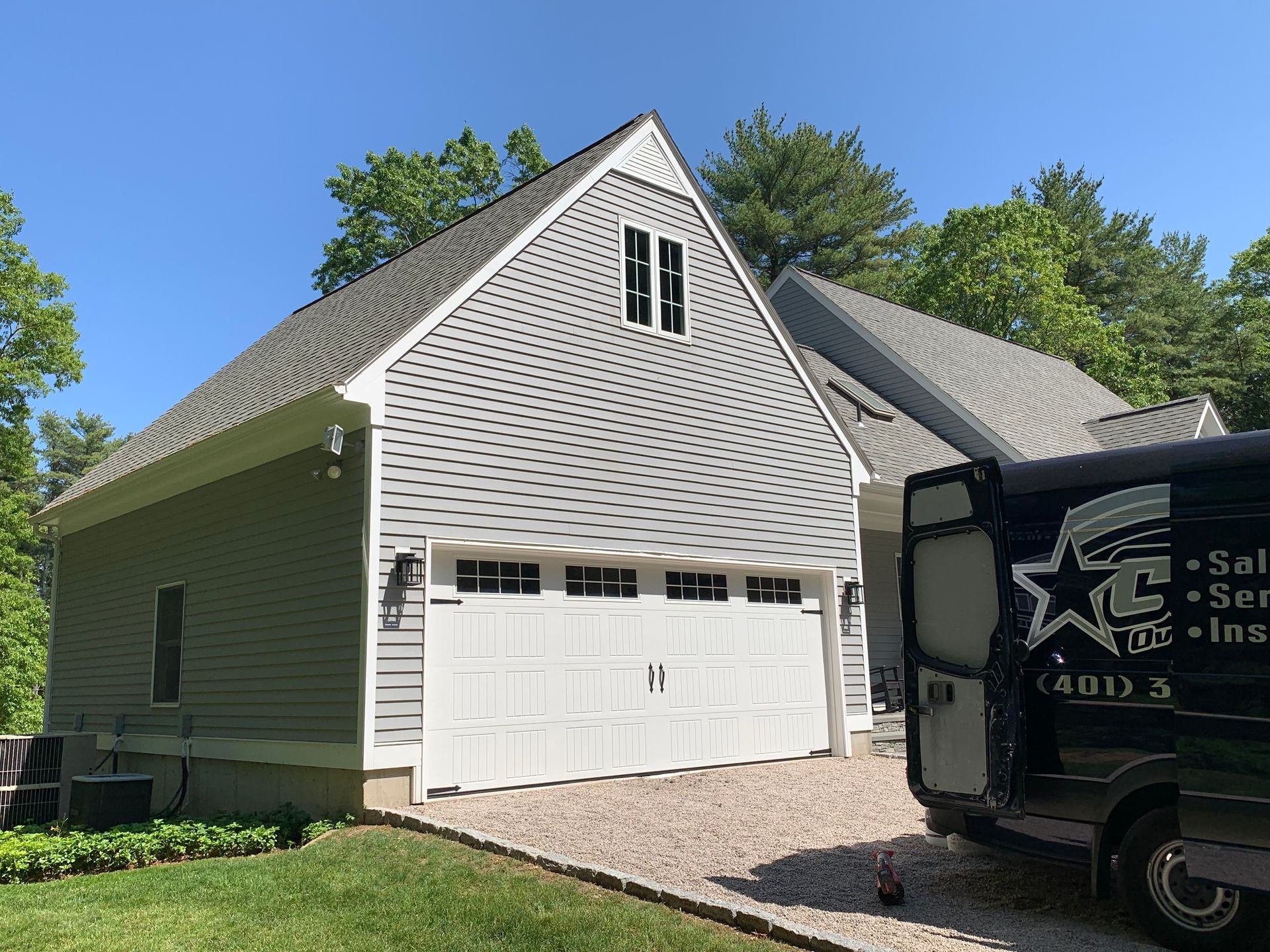 Garage with white door, gray siding, and a service van parked in the driveway.
