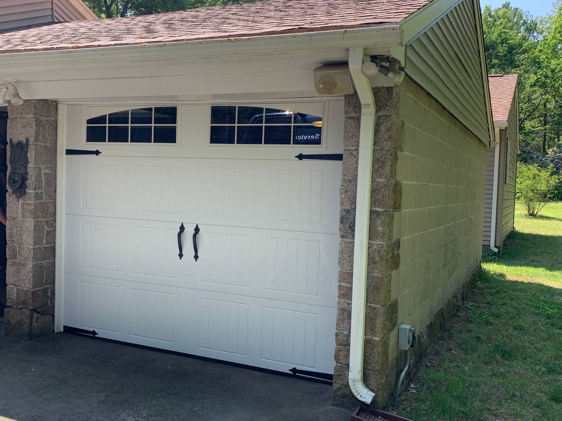 White garage door with black hardware on a light-colored brick building.