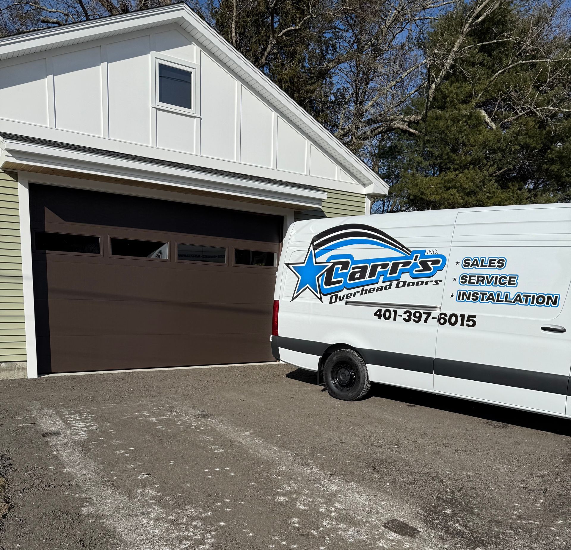 Brown garage door with a white van parked in front. The van has business logos.