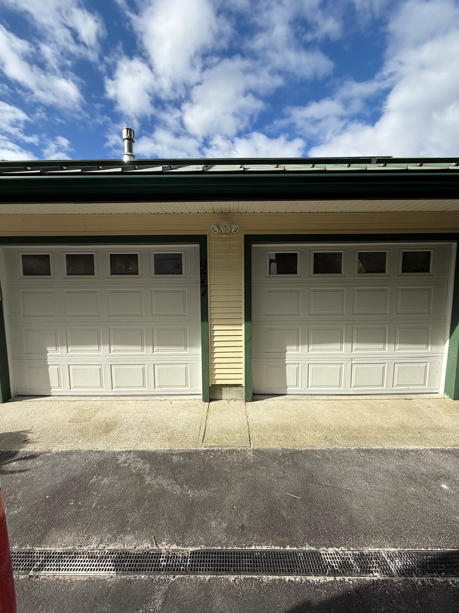 Two white garage doors under a cloudy sky.