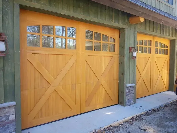 Wooden garage doors with glass panes and an X design, in a green building.