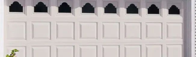 White building facade with arch-shaped window openings at top and square panels below.