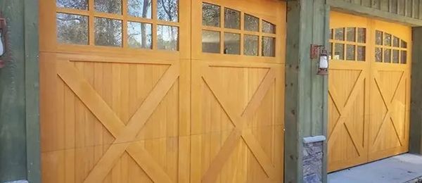 Wooden garage doors with glass windows and an X design.