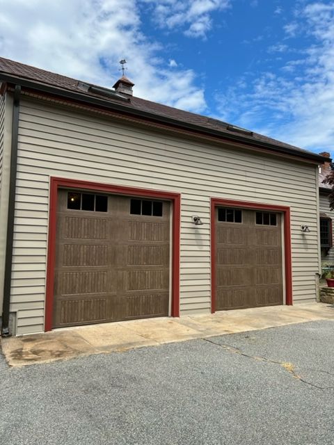Tan garage with two brown doors, red trim, and blue sky.