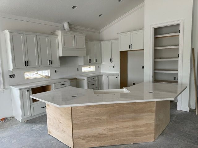 A kitchen with white cabinets and a large island in the middle.