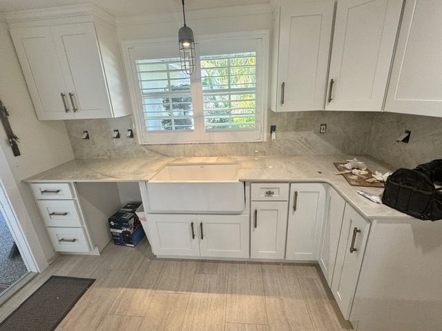 A kitchen with white cabinets and marble counter tops