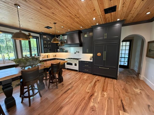 A kitchen with wooden floors , black cabinets and a wooden ceiling.