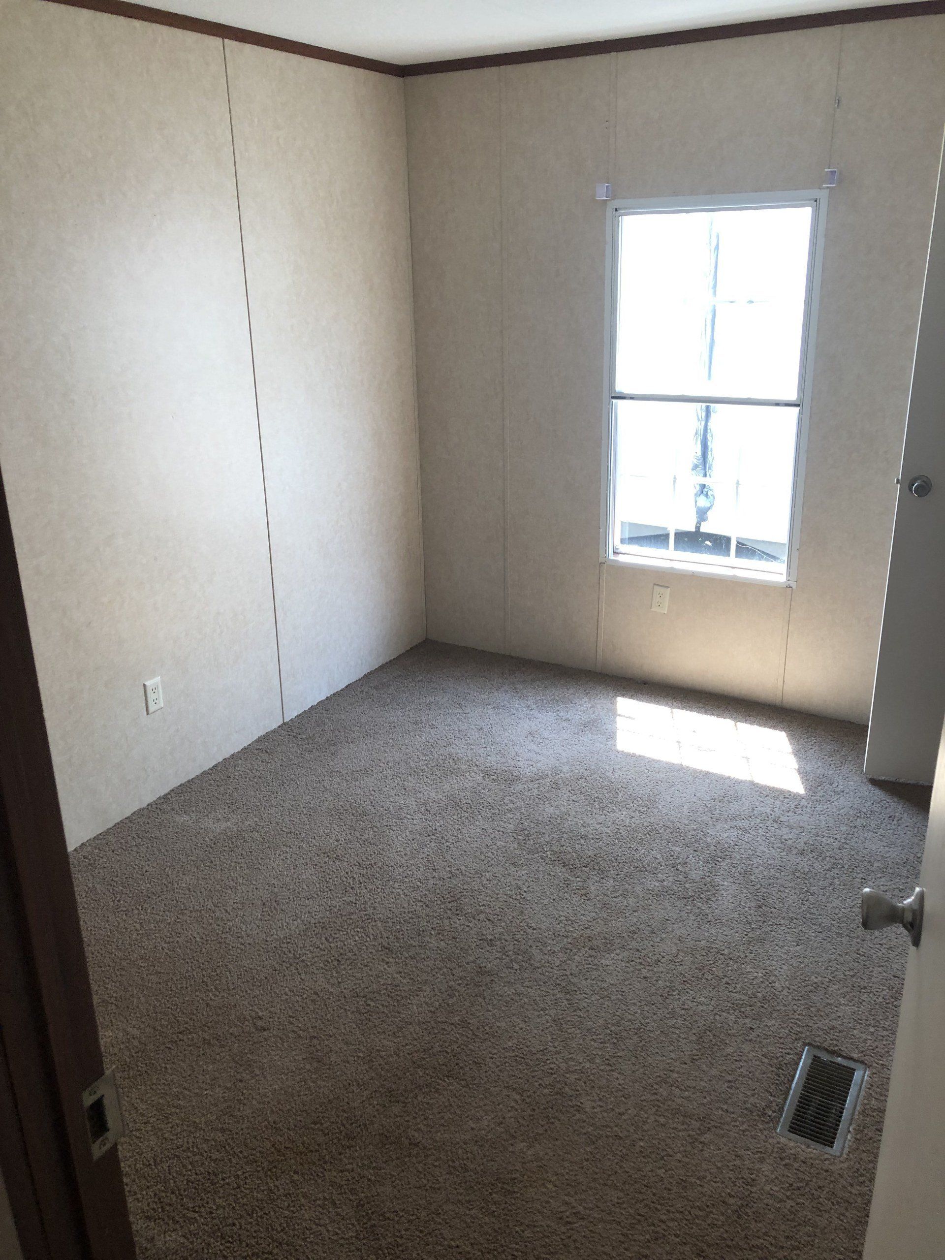 An empty room with a carpeted floor and a window