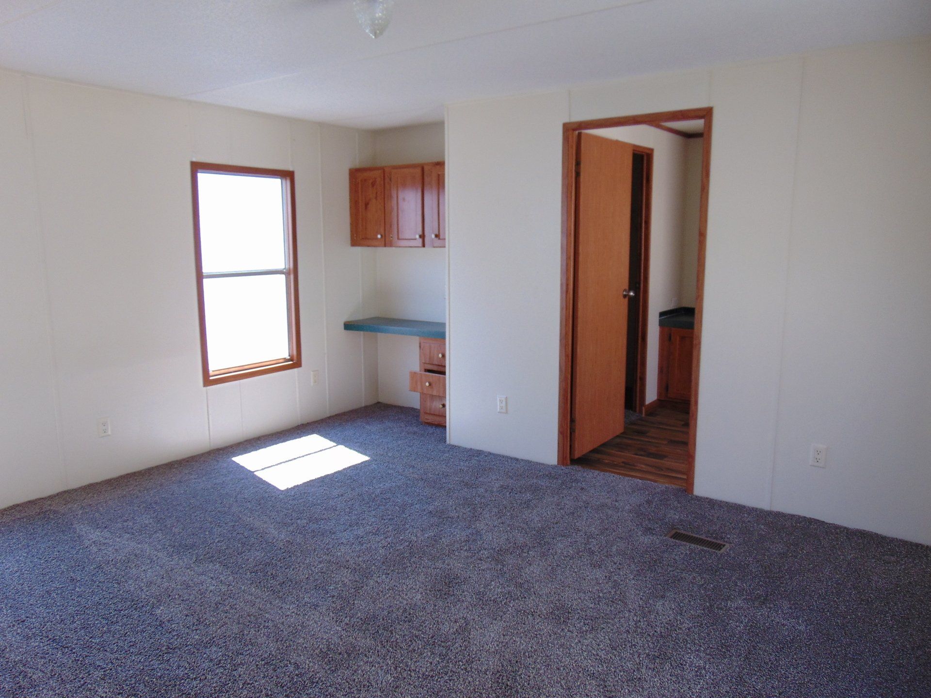 An empty room with a carpeted floor and a window