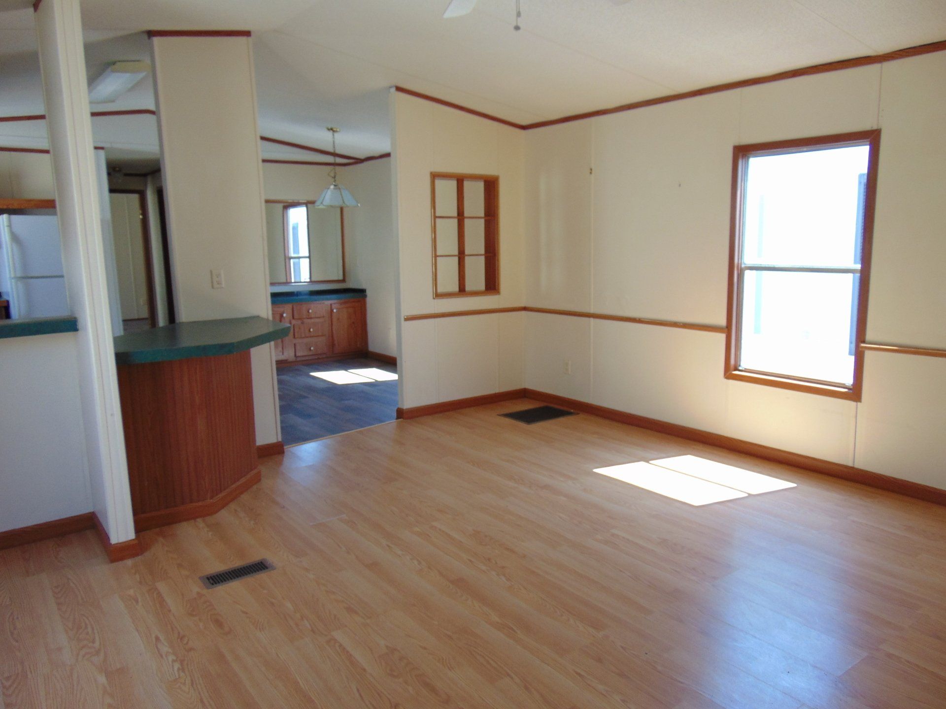 An empty living room with hardwood floors and two windows