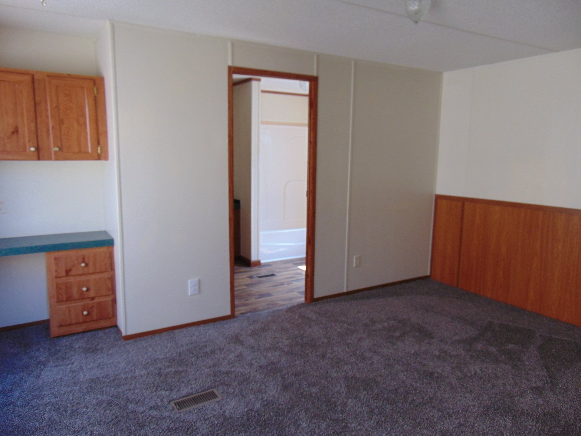 An empty room with a carpeted floor and wooden cabinets