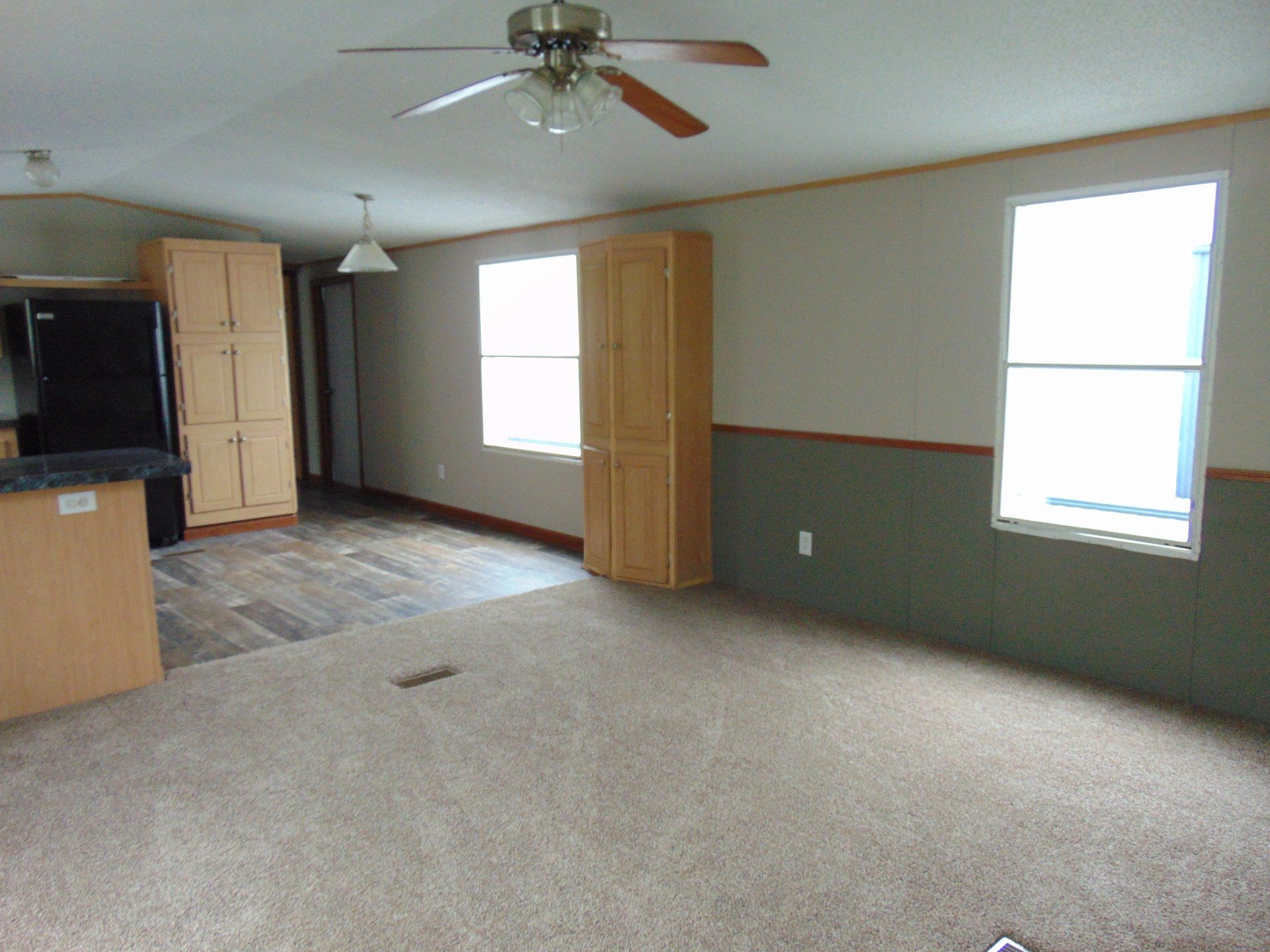 A living room with a ceiling fan and a refrigerator