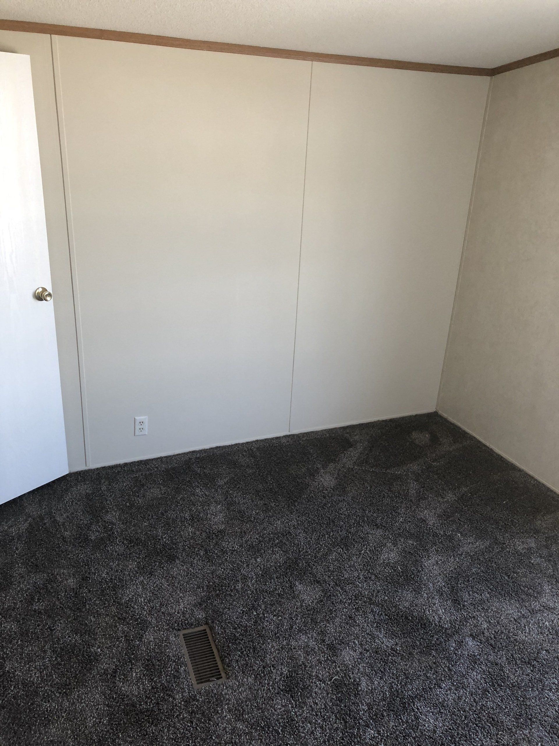 An empty room with a carpeted floor and a door