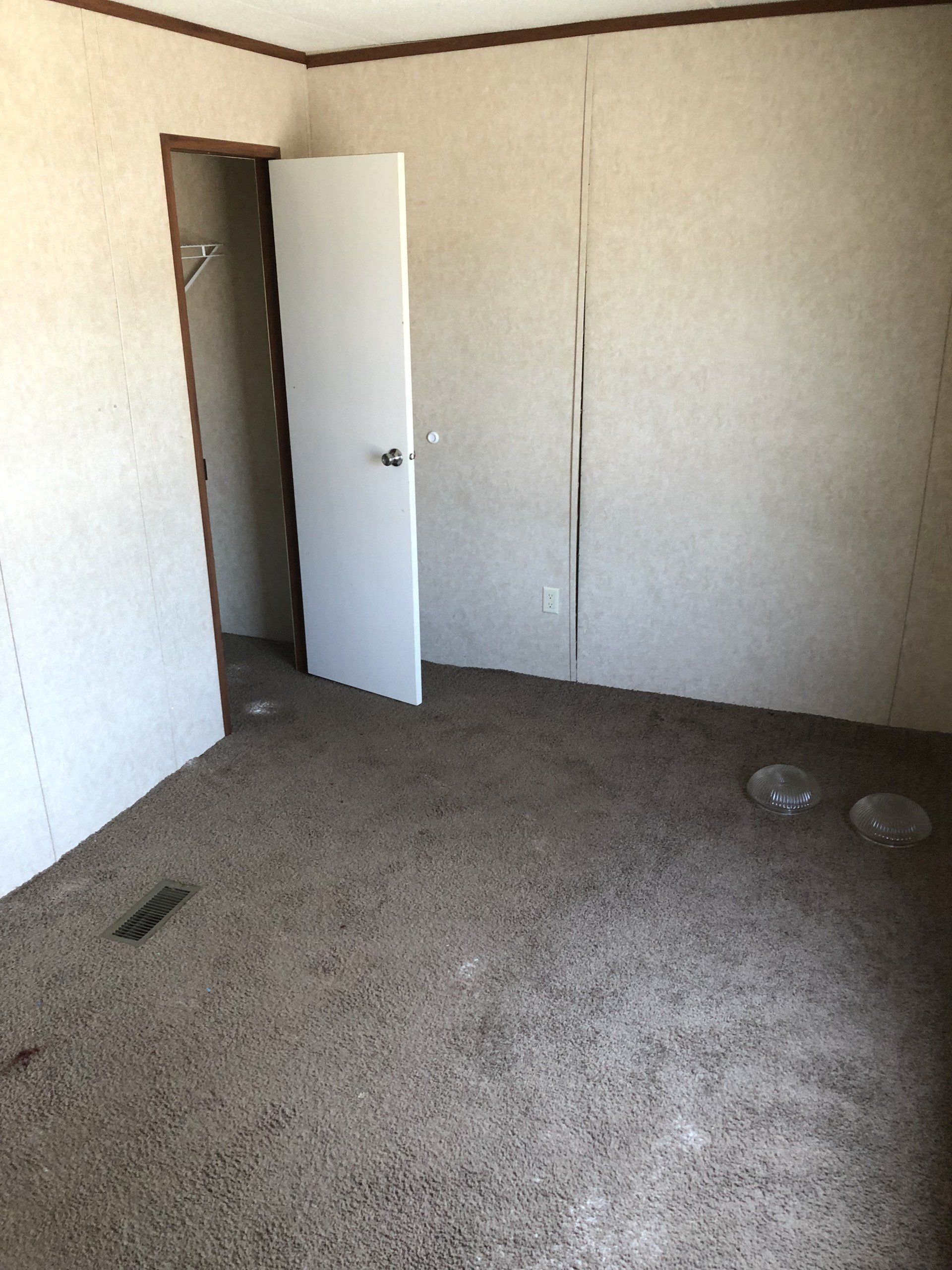 An empty room with a door open and a carpeted floor