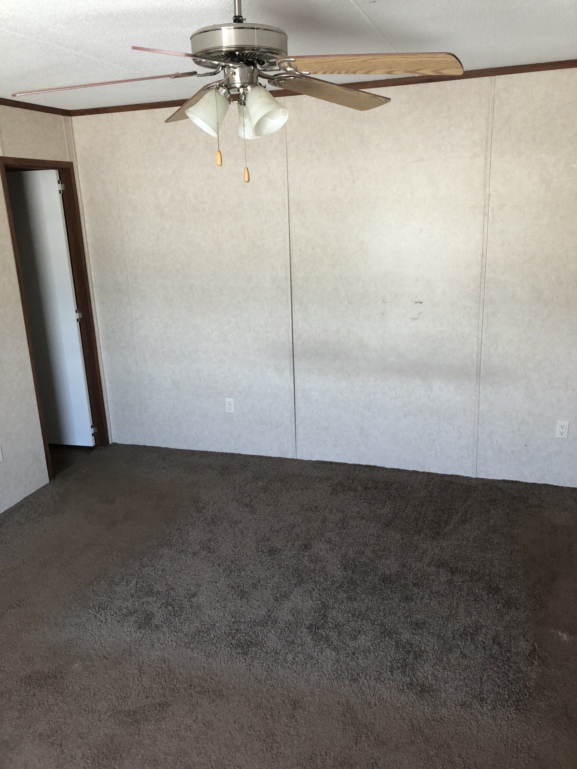 An empty room with a ceiling fan hanging from the ceiling